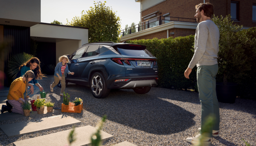 Nové SUV Hyundai TUCSON Shine parkujúce pred domom s rodinou. 