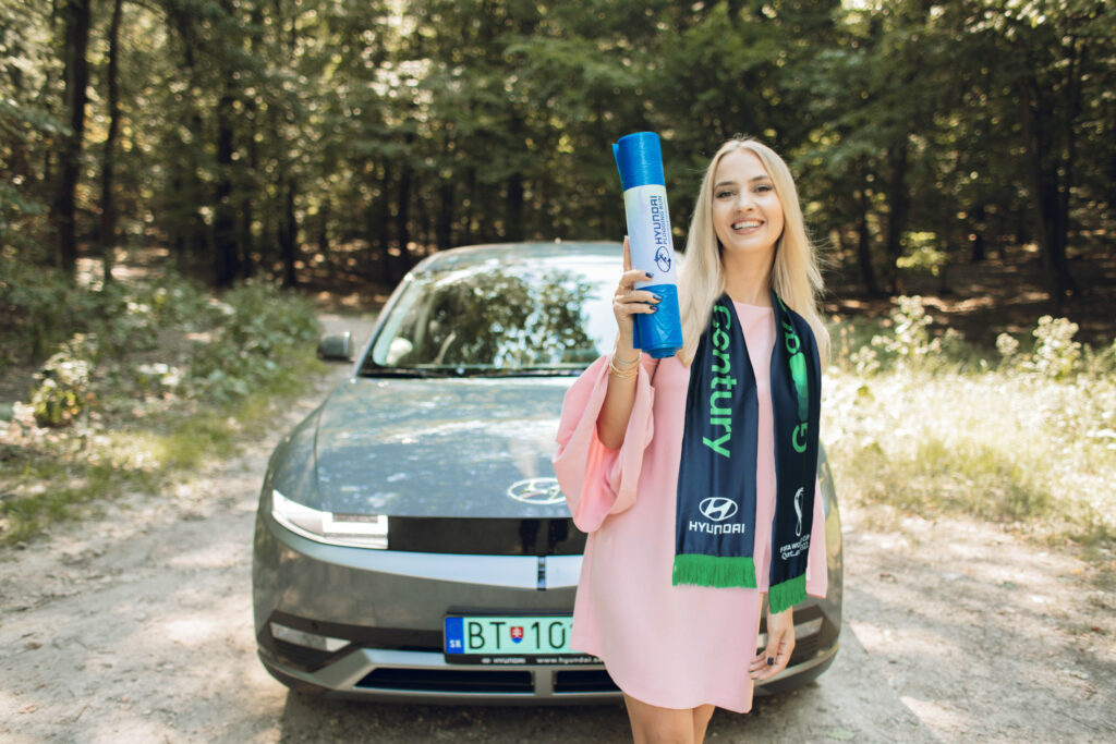 Barbora Krajčírová Rakovská pred modelom Hyundai IONIQ 5, držiac v ruke Plogging kit.